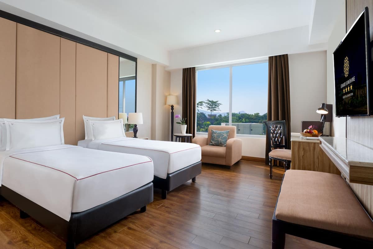 Une chambre d’hôtel avec deux lits, un canapé, un bureau et une télévision.