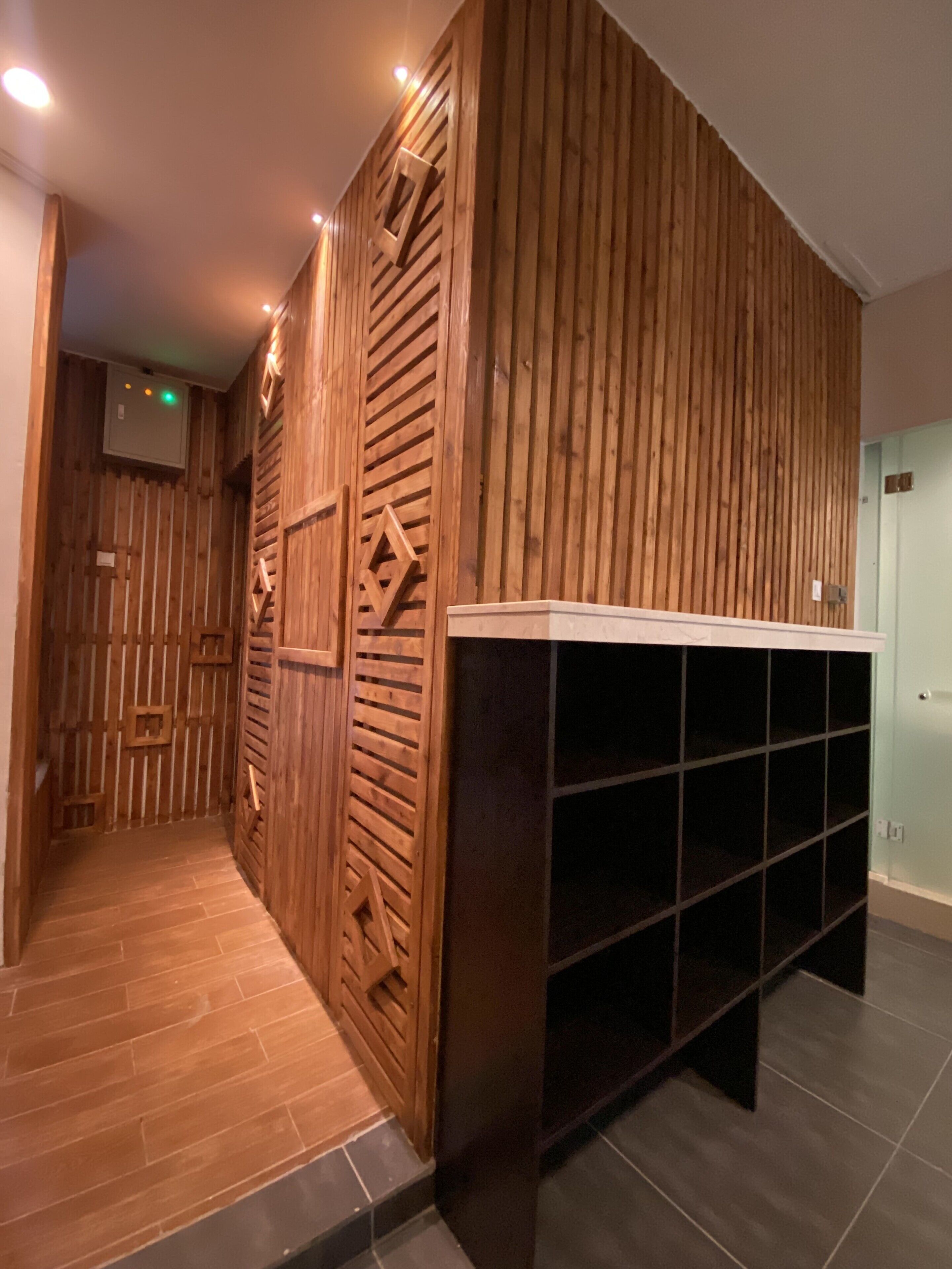 A hallway with wooden paneling and a built-in shelving unit.