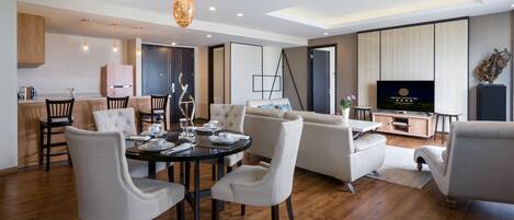 A modern living room with a dining area, a sofa set, a television, and a decorative plant.