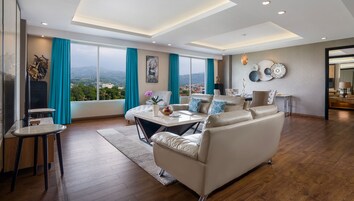 Un salón amplio con un sofá grande, una mesa de comedor y vistas a la ciudad a través de amplias ventanas.