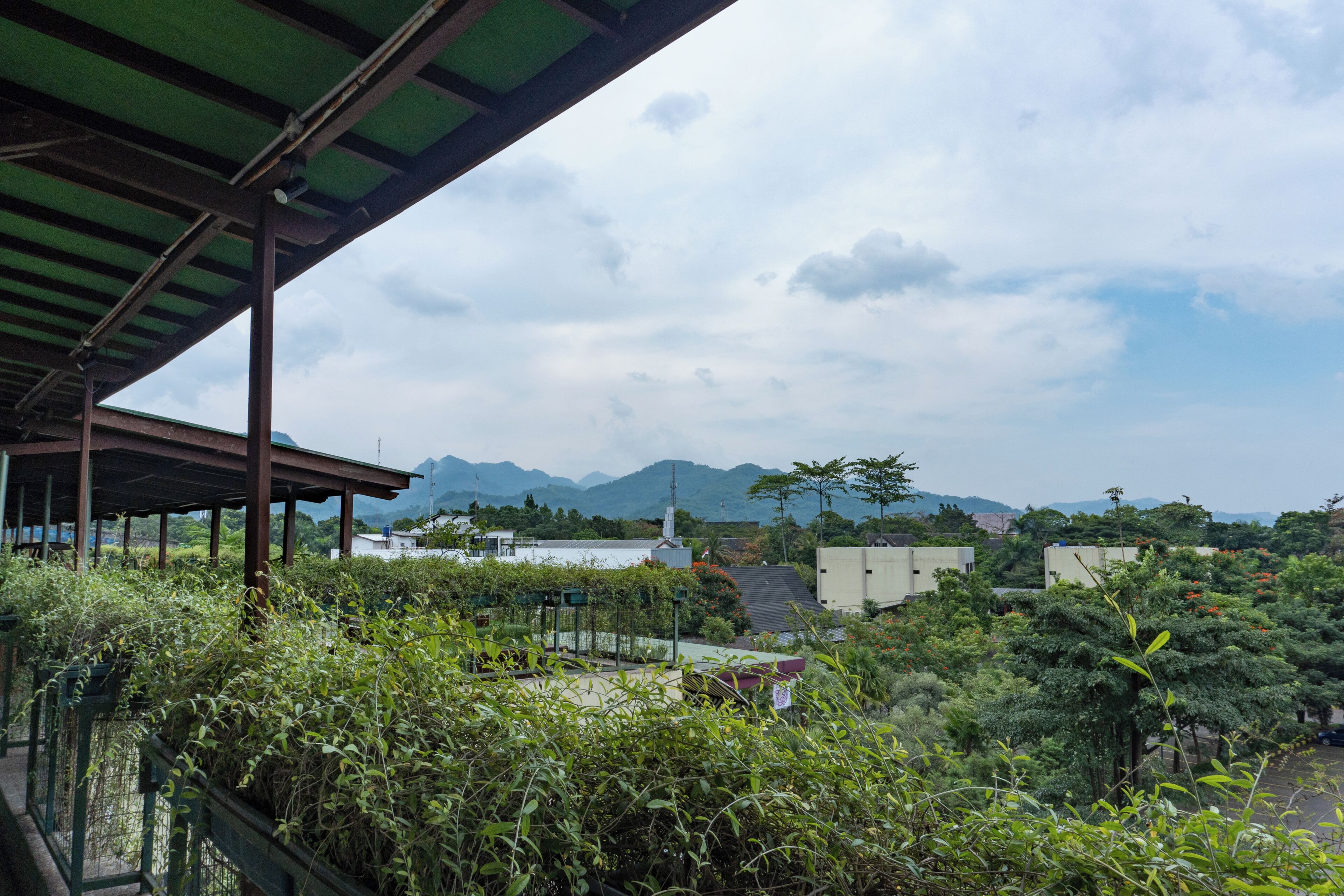 A covered outdoor area with a view of mountains and buildings in the background.