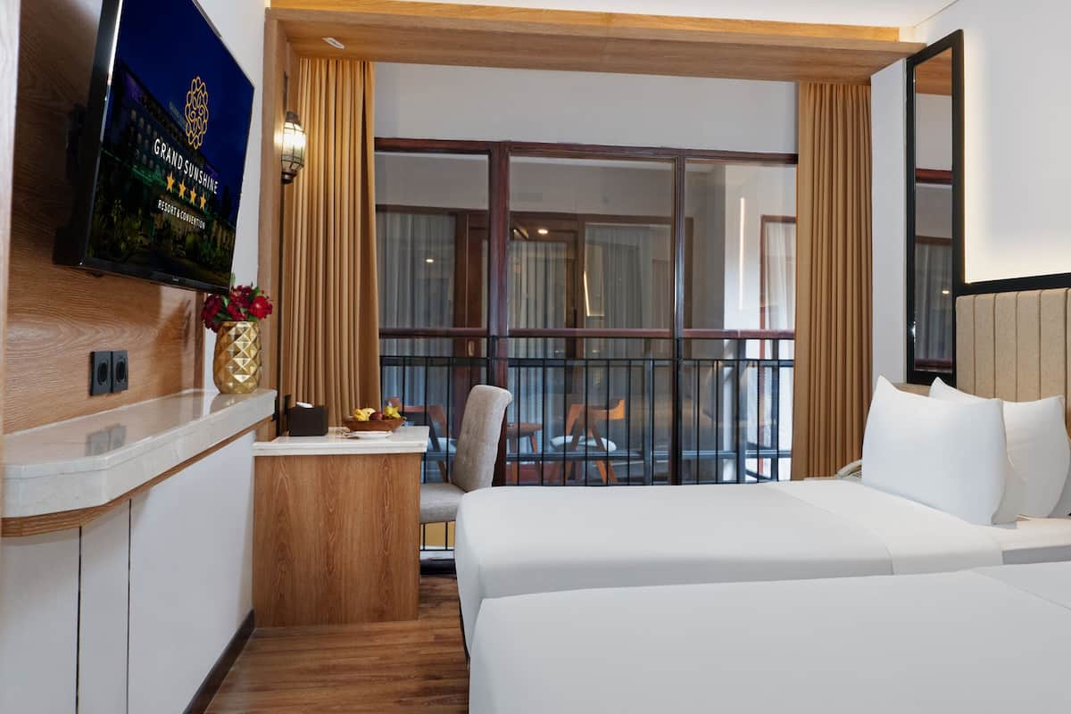 Une chambre d’hôtel avec un lit, un bureau avec une télévision, une fenêtre avec des rideaux et une vue sur l’extérieur.