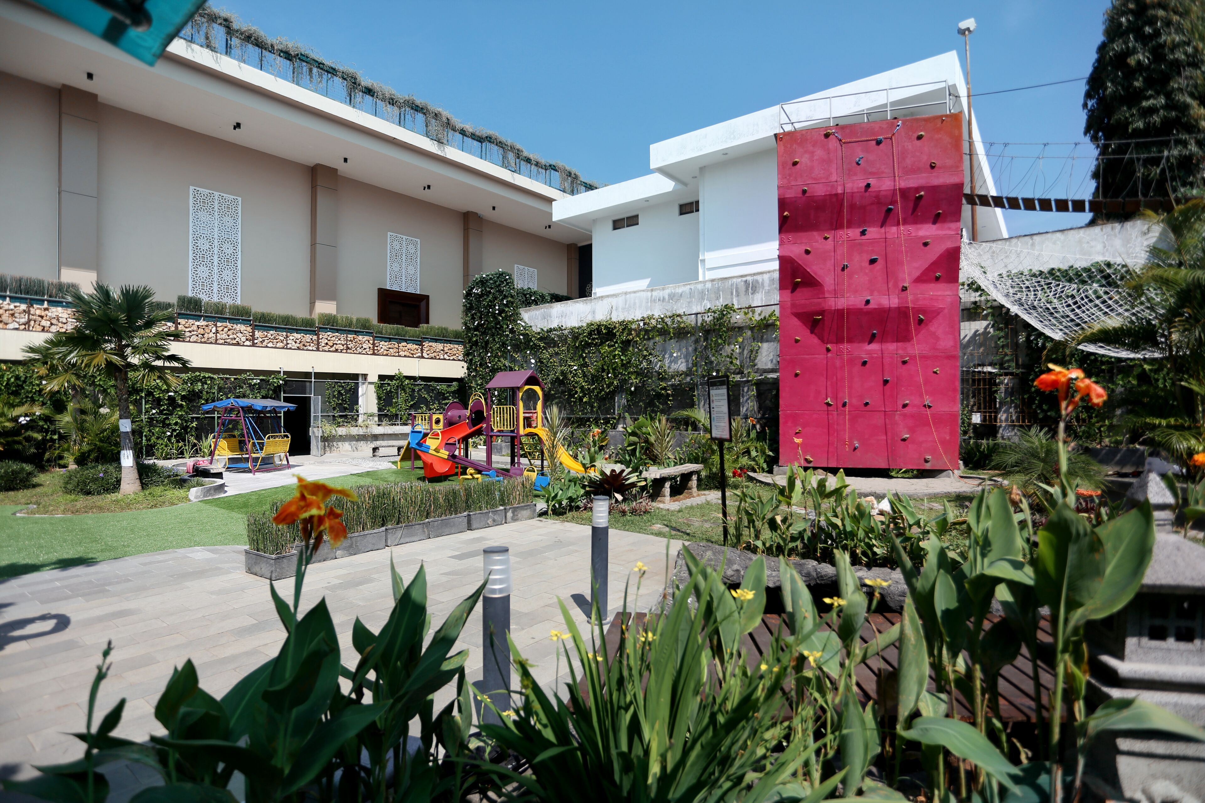 A modern building with a playground and a large climbing wall.