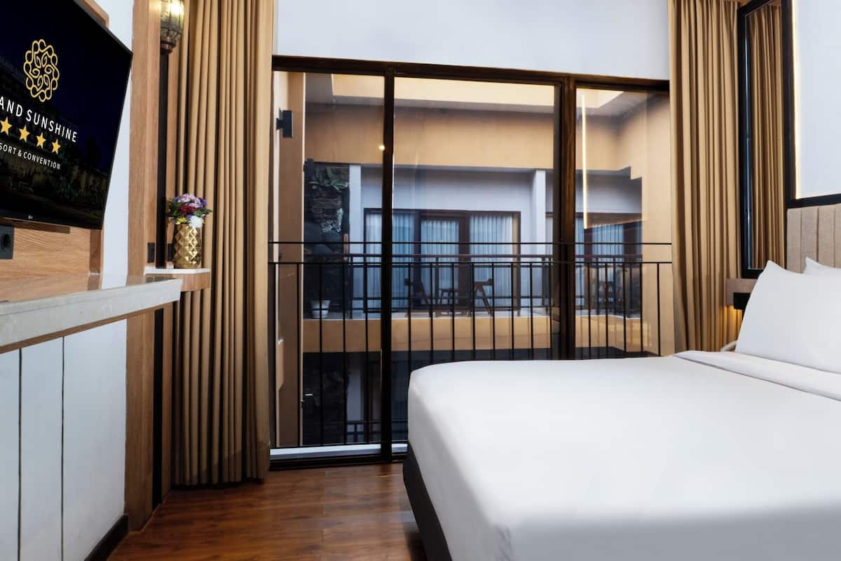 Une chambre d’hôtel avec un grand lit, un balcon avec vue et un panneau sur le mur.