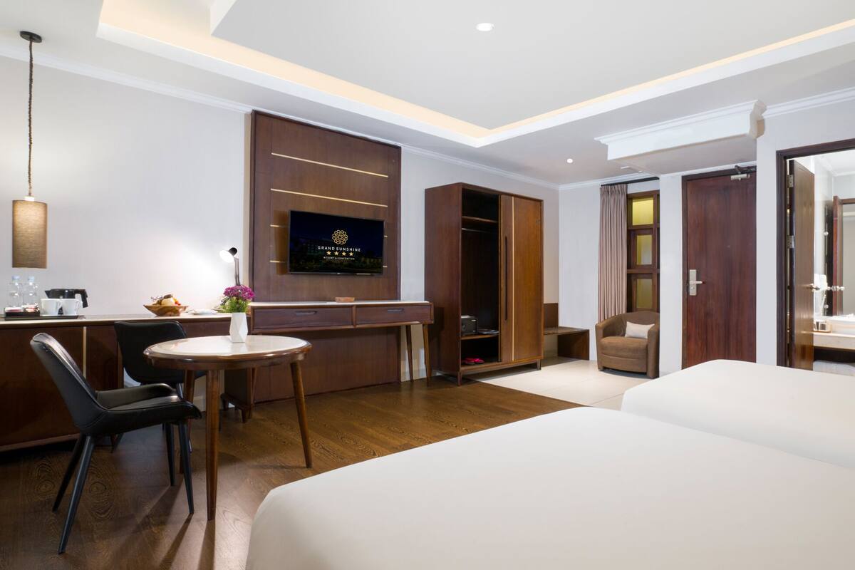 Une chambre d’hôtel comprenant un lit, un bureau avec une chaise, une télévision, une armoire et une salle de bain visible à travers une porte ouverte.