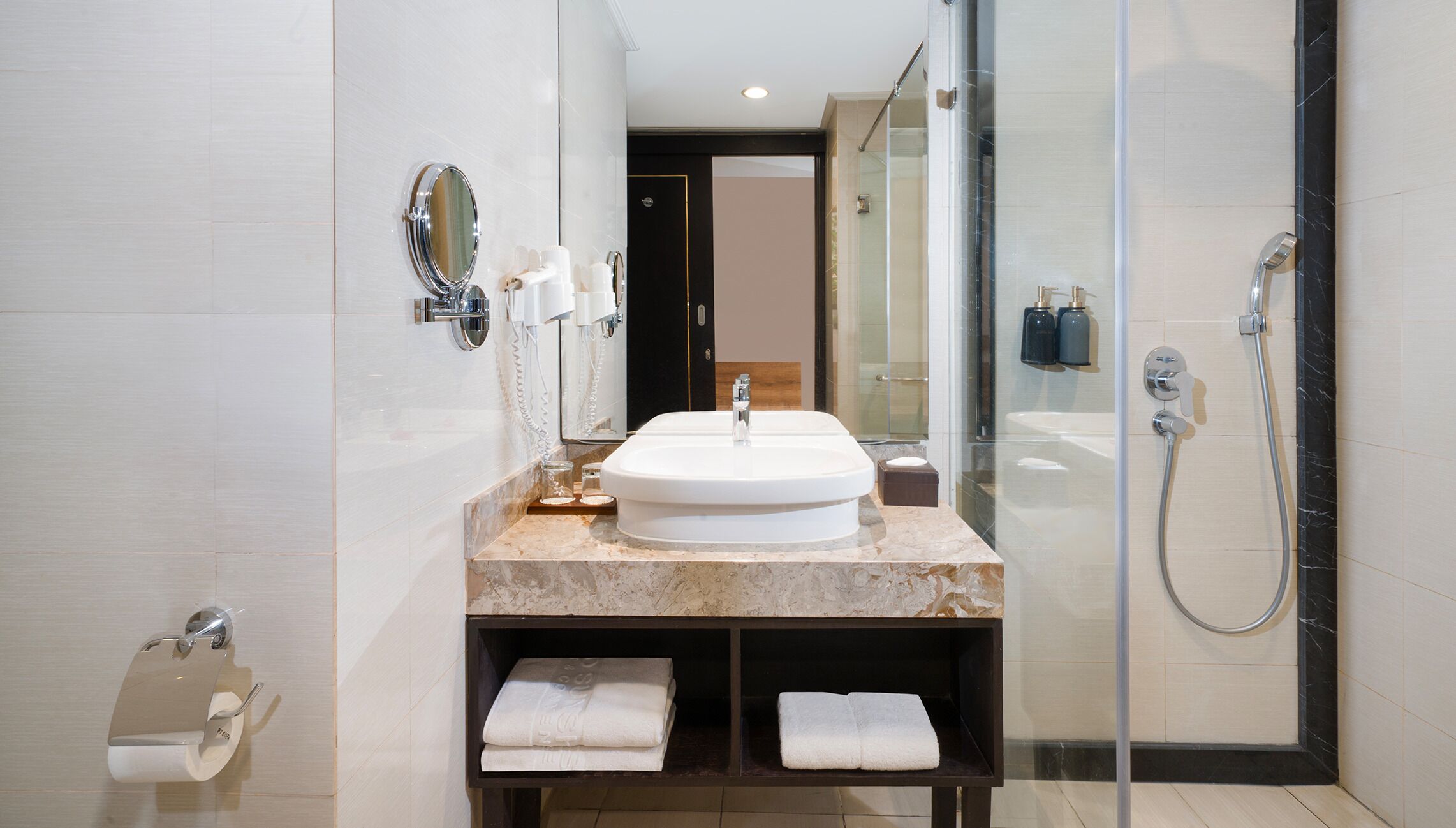 A modern bathroom with a large sink, a mirror, a glass shower enclosure, and a towel rack.