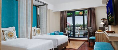 Habitación de hotel con dos camas, un pequeño rincón de descanso, un balcón con vistas y televisión.