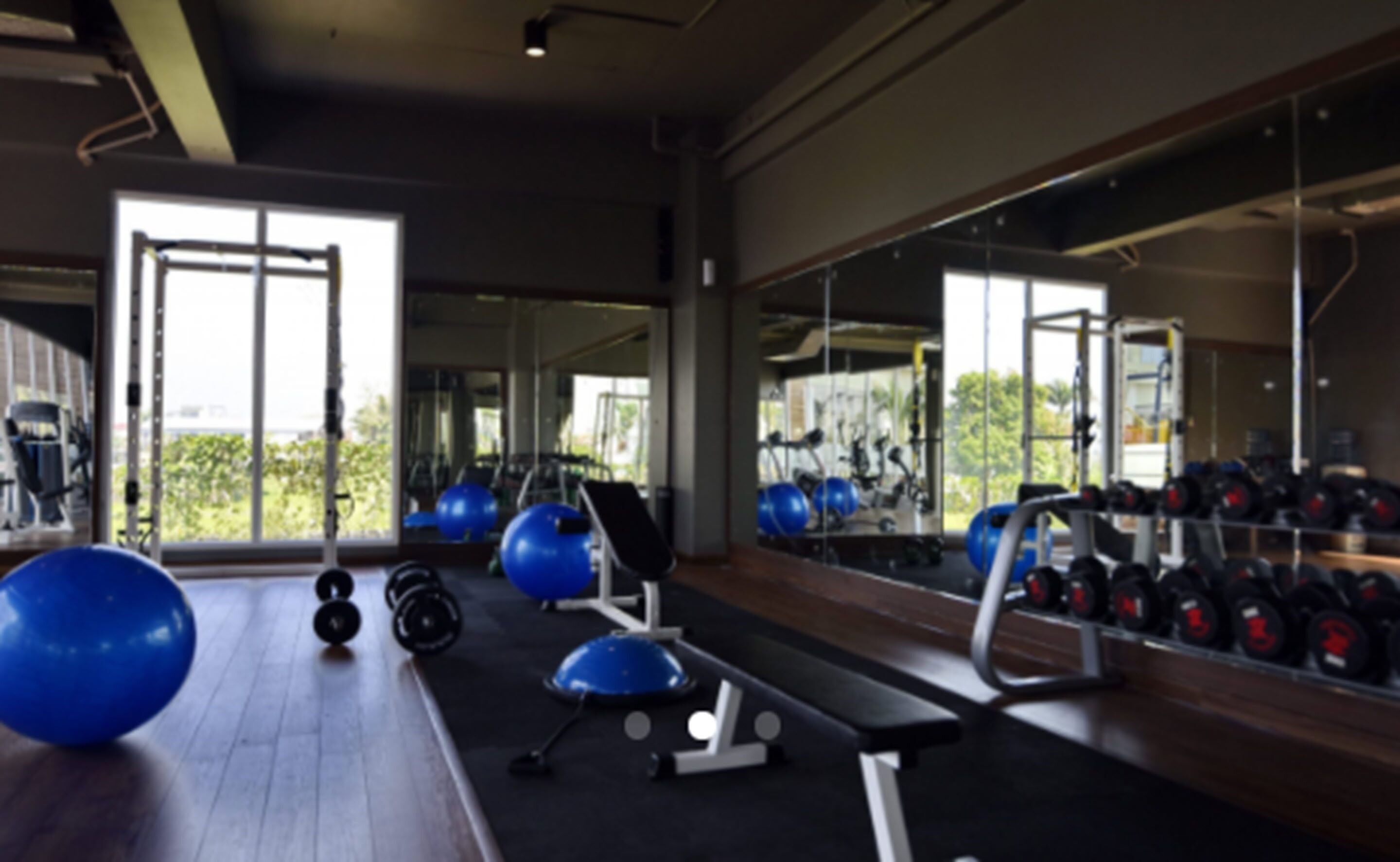 Une salle de sport équipée de matériel d’exercice, d’un banc et d’un grand miroir.