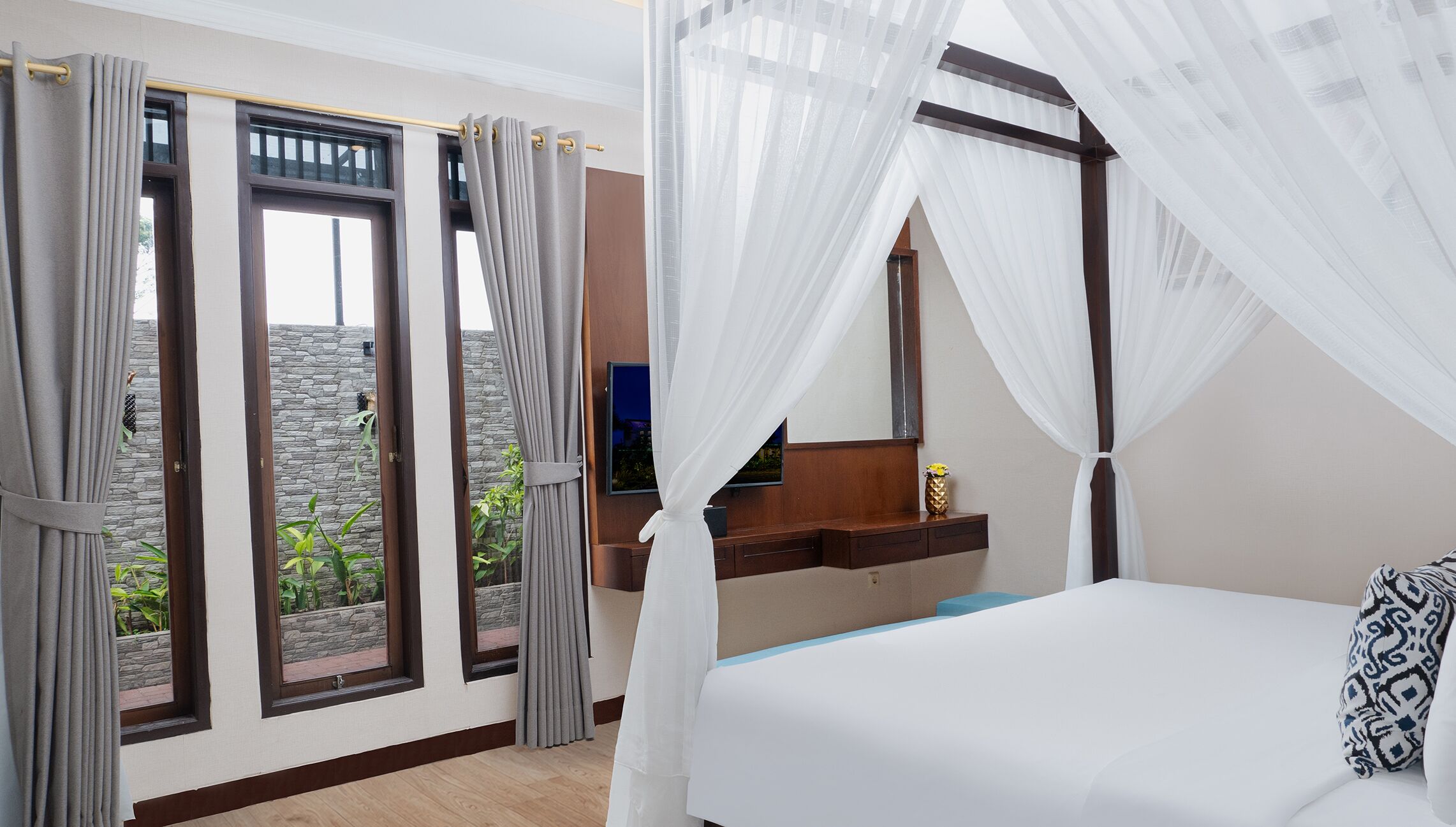 Ein Schlafzimmer mit einem Bett, einem Fernseher und einer Steinfassade vor dem Fenster.