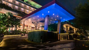 A modern hotel entrance with a covered walkway, palm trees, and a well-lit facade. - Grand Sunshine Resort & Convention (Soreang)