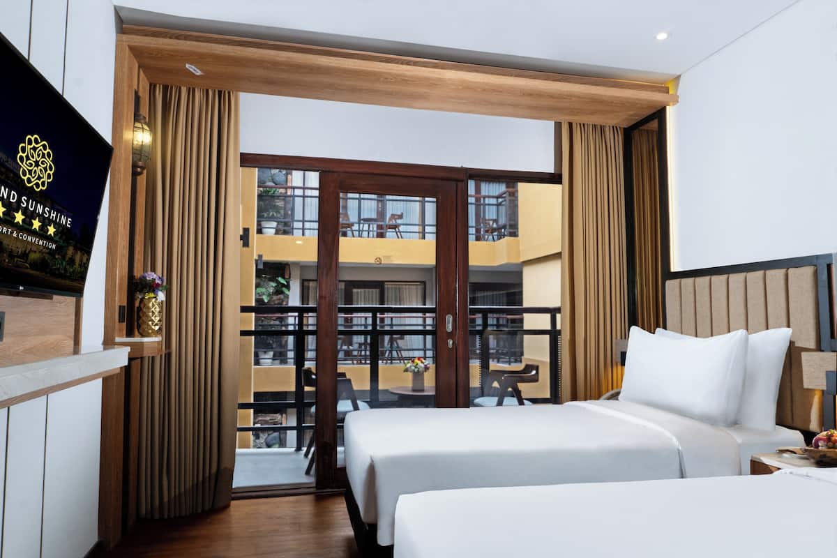 Une chambre d’hôtel avec deux lits, un balcon et une vue sur l’espace extérieur.