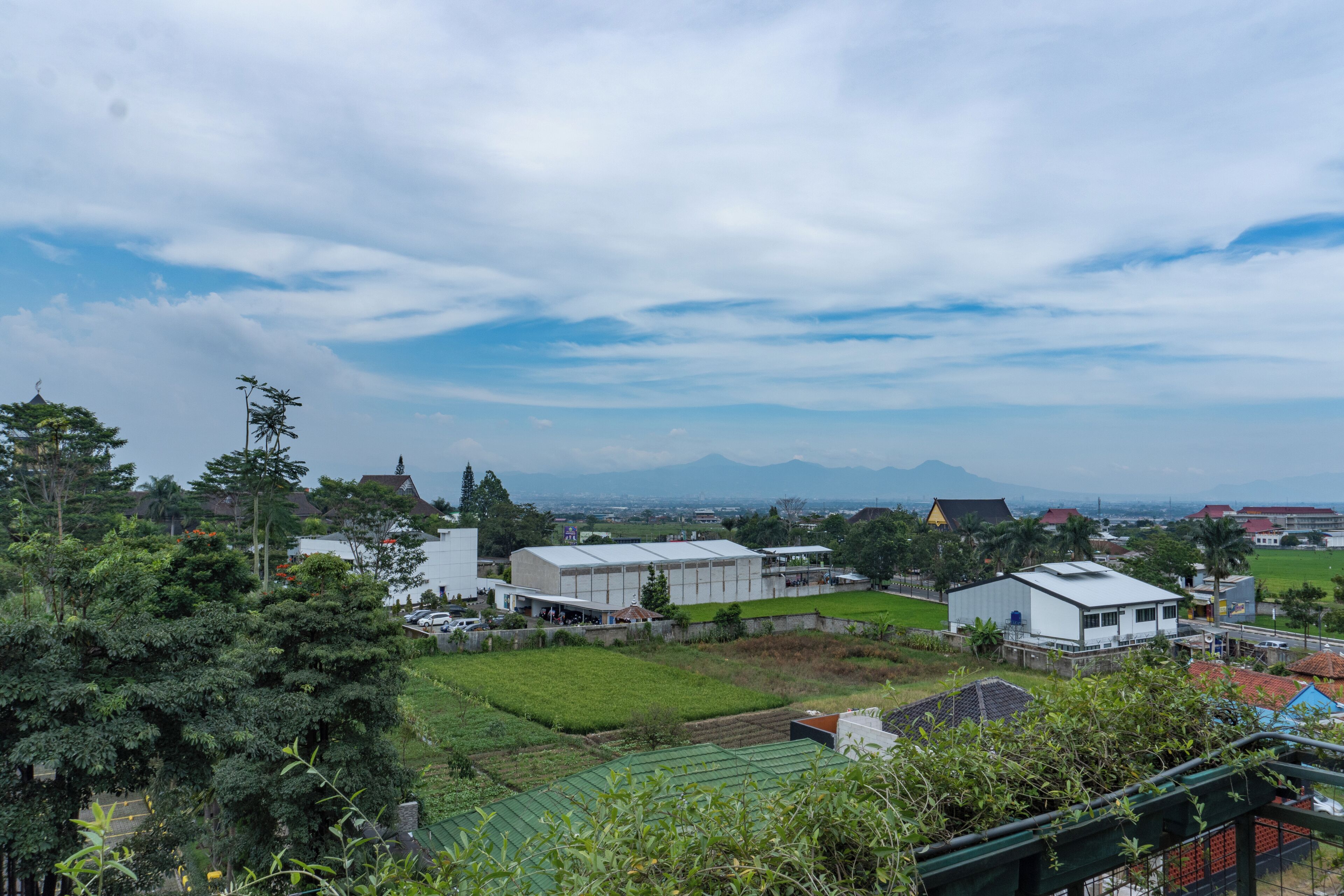 A residential area with houses, a large building, and a green field.