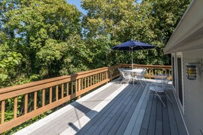 Enjoy a serene outdoor space with a table and chairs under a shaded area surrounded by lush greenery.