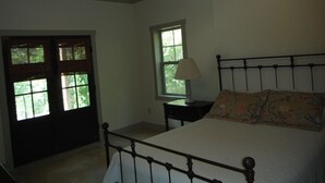 A bedroom with a bed, a window, a nightstand, and a ceiling fan. - Lake Wedowee Privacy (Wedowee)