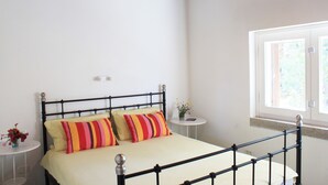 A bedroom with a bed, a small round table, and a window with a view of greenery. - House With Sea View On Elba Island - 10 Min Walk from Beach (La Guardia)
