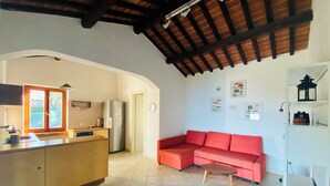 A kitchen with a refrigerator, a sink, and a window. There is a red sofa and a clock on the wall. - House With Sea View On Elba Island - 10 Min Walk from Beach (La Guardia)