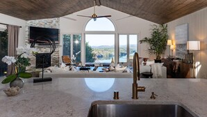 Een moderne keuken met een groot eiland, een inbouwoven en uitzicht op een meer.