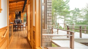 Un interior de madera con comedor, chimenea y vistas al exterior.