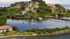 A coastal area with a hilltop building complex, a marina with boats, and a rocky shoreline. - Summer in Playa Flamingo Costa Rica. 2bd/2bath Sleeps 6 Ocean View,new upgrade (Playa Flamingo)