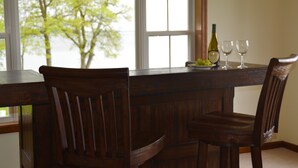 A wooden dining table with two chairs, a bottle of wine, and two wine glasses on it. - Sunset Lodge on the Bay (Rock Hall)