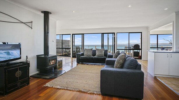 A spacious living area with a large TV, a fireplace, and a sofa with cushions. - IL Mare (expansive ocean views)  (Apollo Bay/ Skenes Creek)