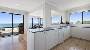 A modern kitchen with large windows, a view of the sea, and a dining area with a view. - IL Mare (expansive ocean views)  (Apollo Bay/ Skenes Creek)