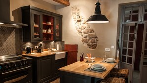 Una cocina con armarios oscuros, salpicadero de azulejos, una isla de madera y una pared decorativa de piedra.