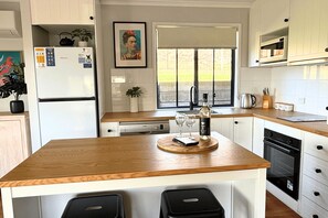 A modern kitchen with a wooden countertop, a built-in dishwasher, and a large window.