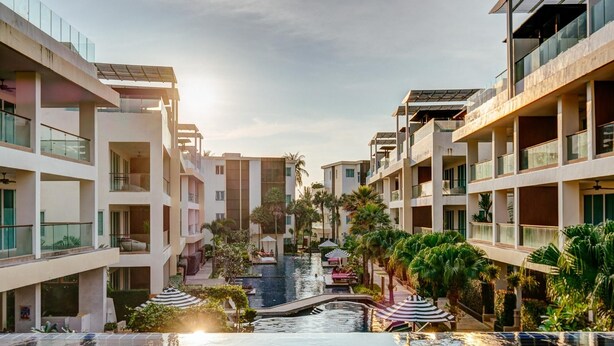 A hotel with multiple floors, outdoor swimming pools, and palm trees. - Sunset Bliss Andaman Sea View (Klong Muang)