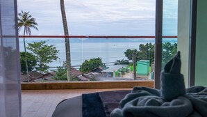 A room with a view of the sea, a bed, and a window with a view of the sea and palm trees. - Sunset Bliss Andaman Sea View (Klong Muang)