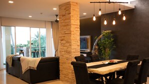 A modern dining area with a stone pillar, black upholstered chairs, and a wooden table. - Sunset Bliss Andaman Sea View (Klong Muang)