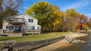 A lakeside cabin with a deck and outdoor seating, surrounded by autumn-colored trees. - 5-bedroom vacation home 5 minutes from historic Charlestown (Perryville)