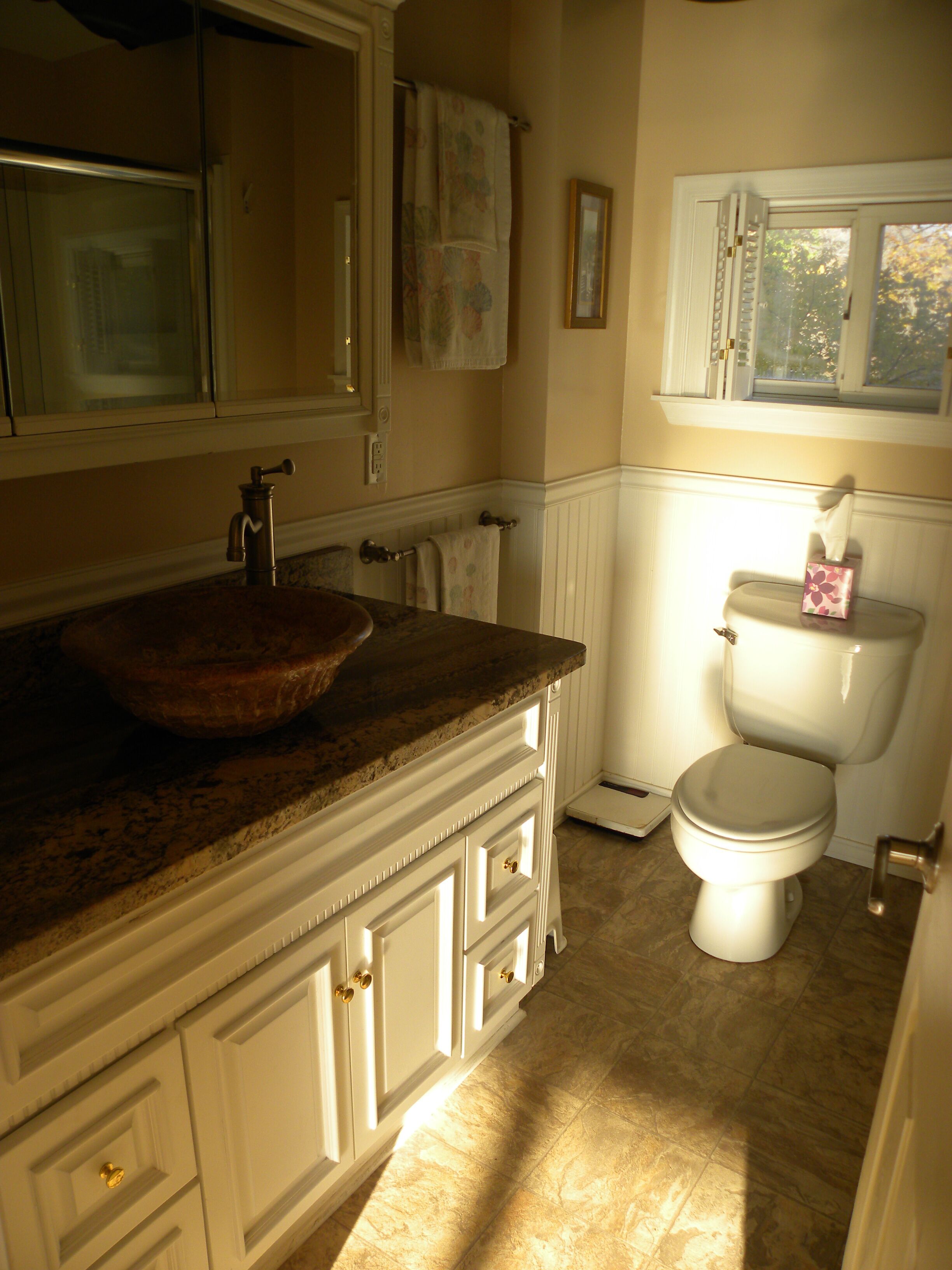 A bathroom with a marble sink, a toilet, and a window.