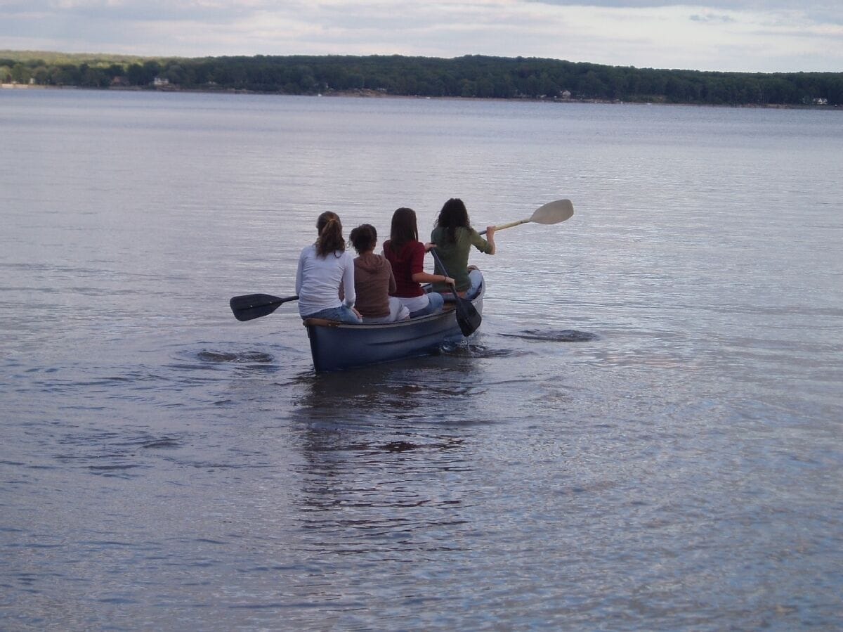 A small rowboat with four people on a calm lake.