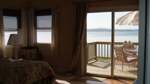 A bedroom with a bed, a nightstand, and a window overlooking a deck with outdoor furniture. - 5-bedroom vacation home 5 minutes from historic Charlestown (Perryville)