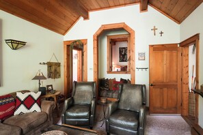 A cozy living room with leather chairs, a wooden ceiling, and a door with a cross. - Luxury Cottage at Sundance Utah-Book Fall Leaf Stay-Walk to Lift and Restaurants (Sundance)
