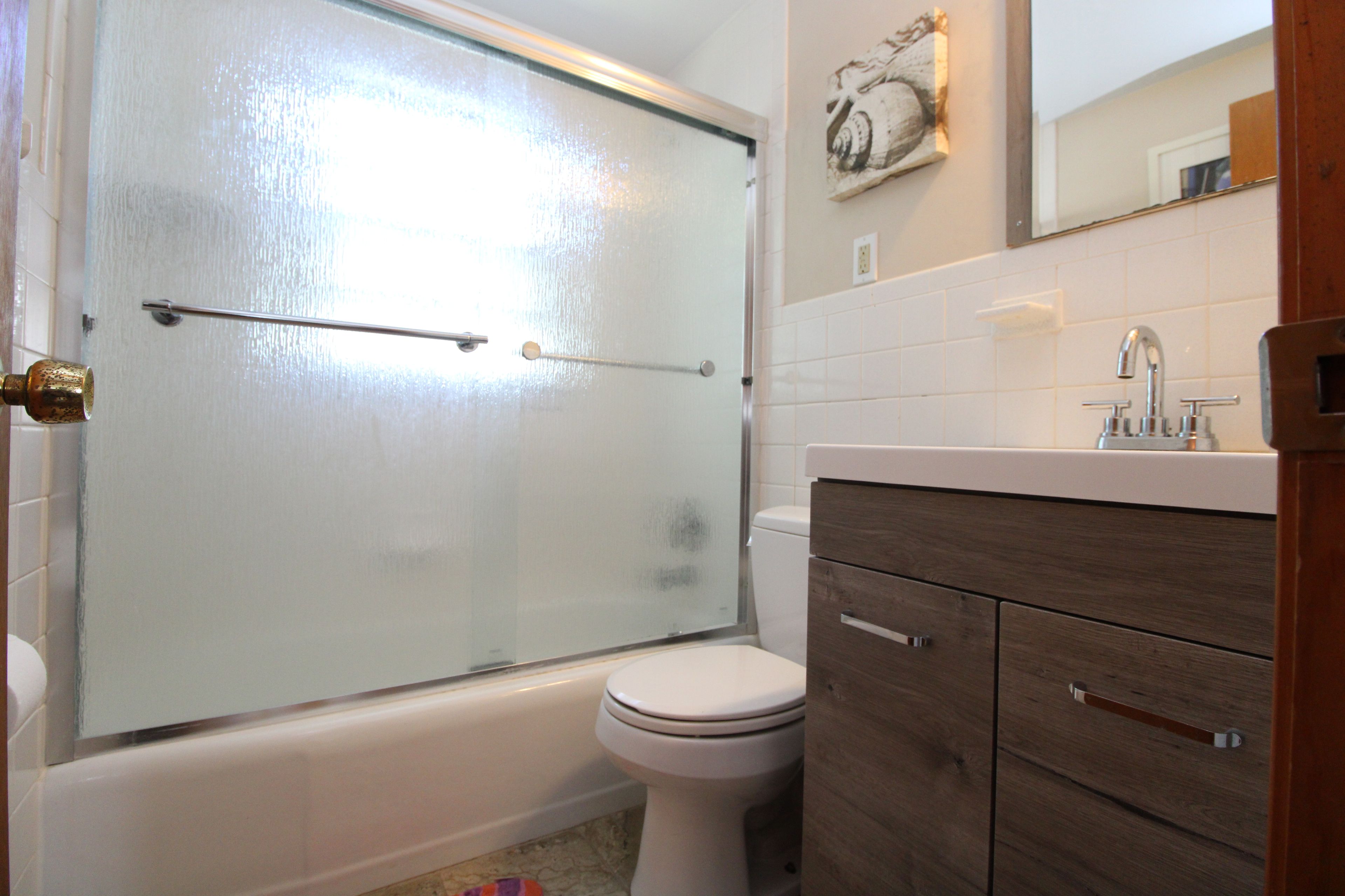 A bathroom with a glass shower enclosure, a white toilet, and a wooden vanity with a sink.