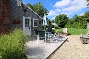 A wooden deck with outdoor furniture, a grill, and a patio umbrella. - Updated Dennis Port Cottage Near Nantucket Sound (2069) (Dennis Port)