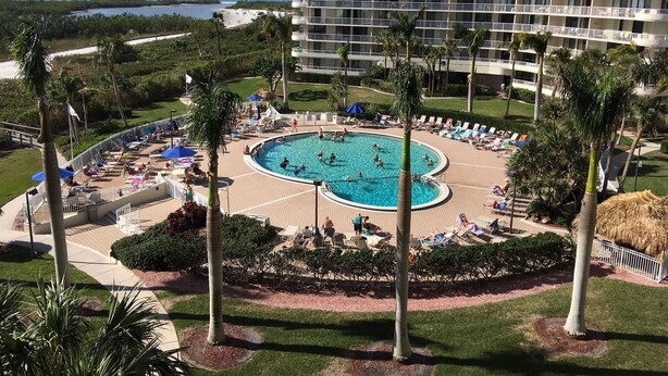 A hotel with a large pool surrounded by palm trees and lounge chairs. - Beachfront 2BR in South Seas T3-508 with Updated Kitchen! (Marco Island)