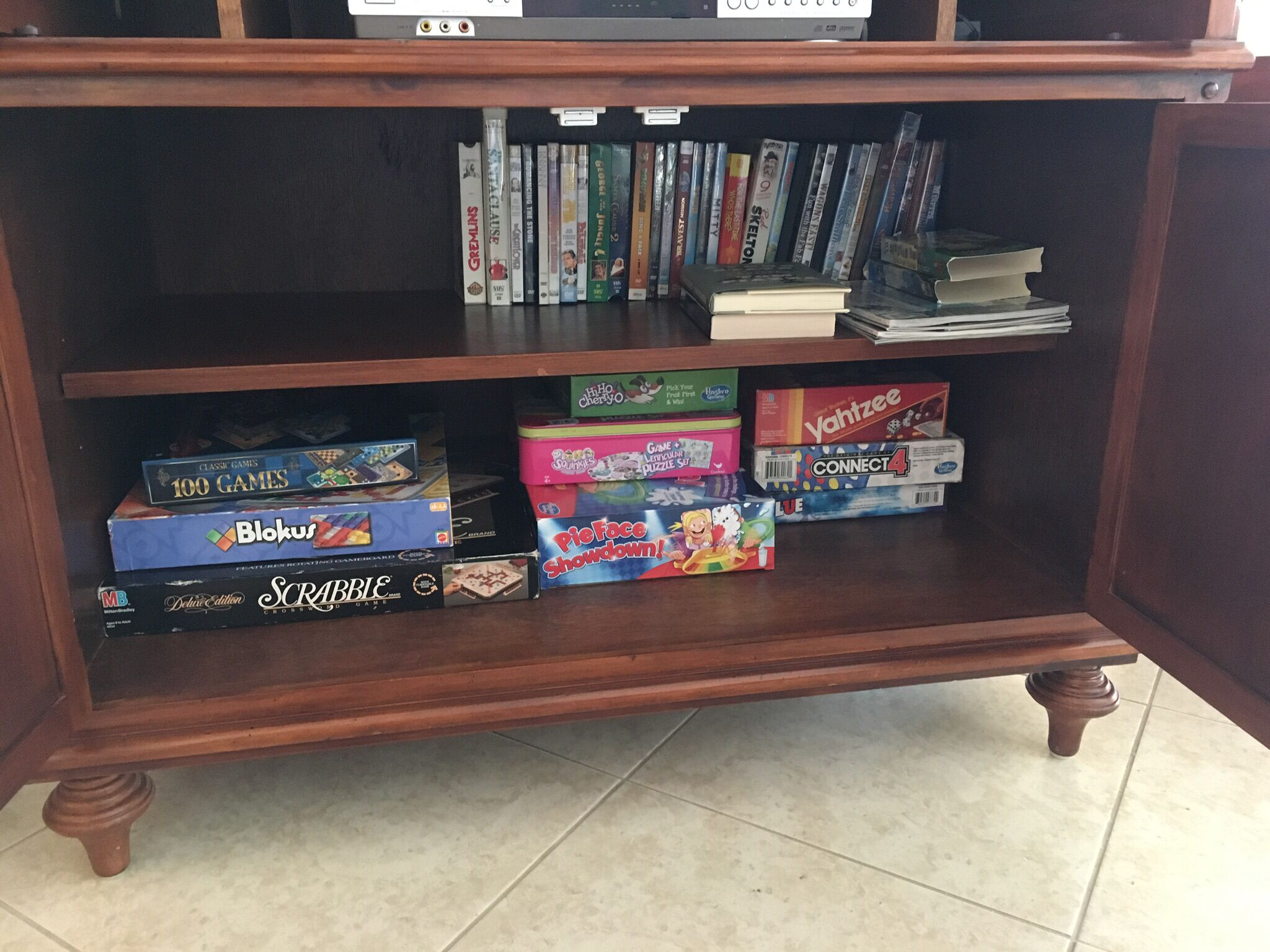 A wooden shelf with various board games and DVDs.