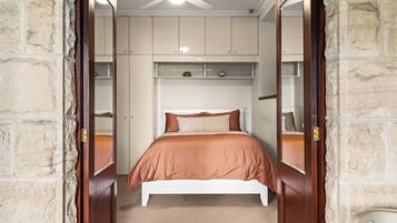 A bedroom with a bed, a ceiling fan, and built-in shelving.