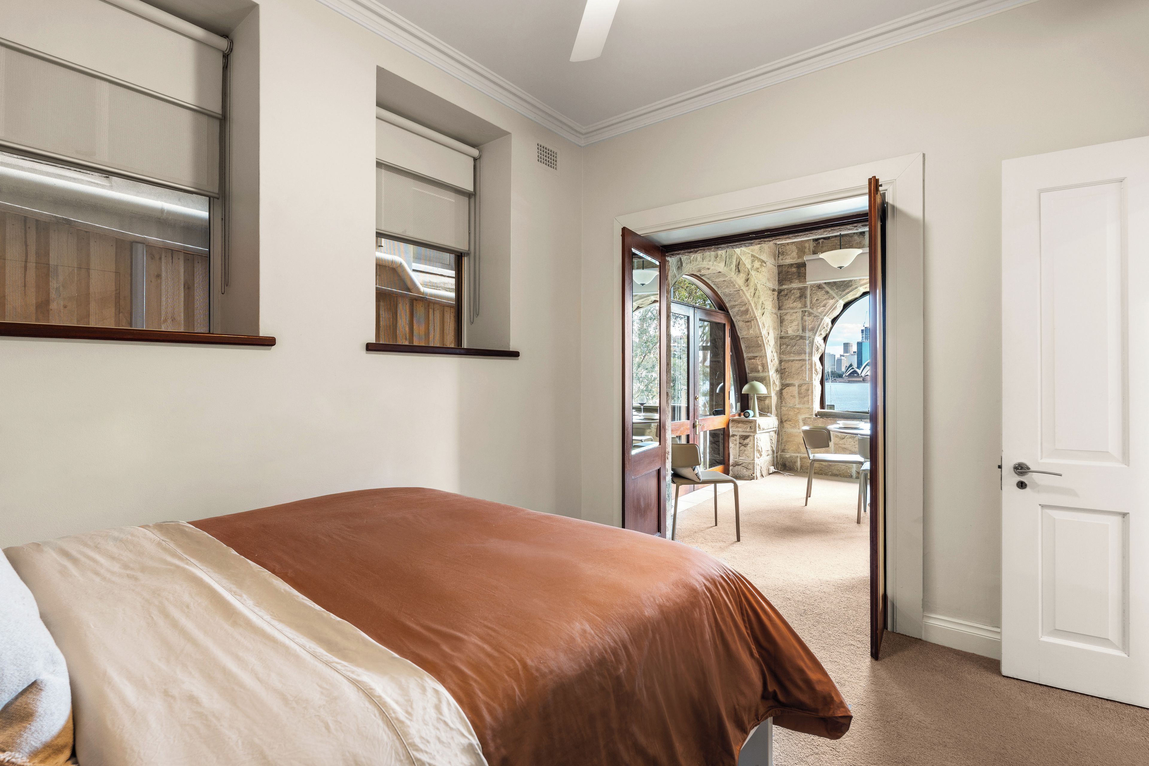 A bedroom with a bed, a door leading to a balcony, and a view of the cityscape.