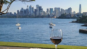 Vista para a frente marítima com veleiros, um copo de vinho tinto e uma tábua de queijos.