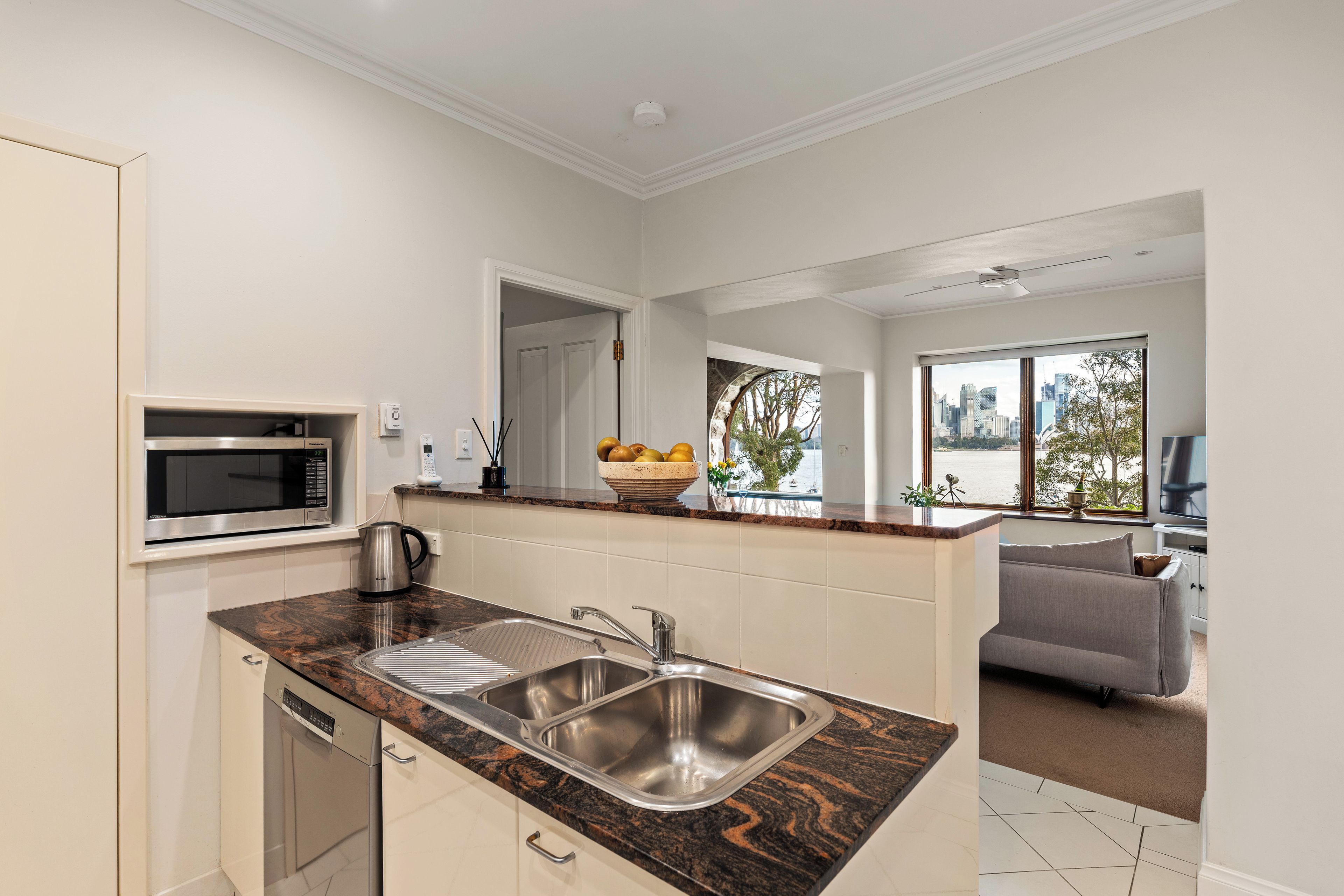 A modern kitchen with a double sink, a built-in microwave, and a kettle.