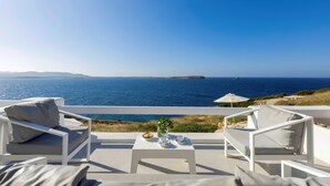 Eine Terrasse mit weißen Möbeln mit Blick auf das Meer.