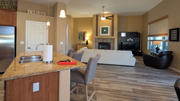 A spacious living area with a kitchen island, a fireplace, and a seating area with a sofa and chairs. - Casa Bella-Luxury home on corner lot, bring your fur baby. (Oro Valley)