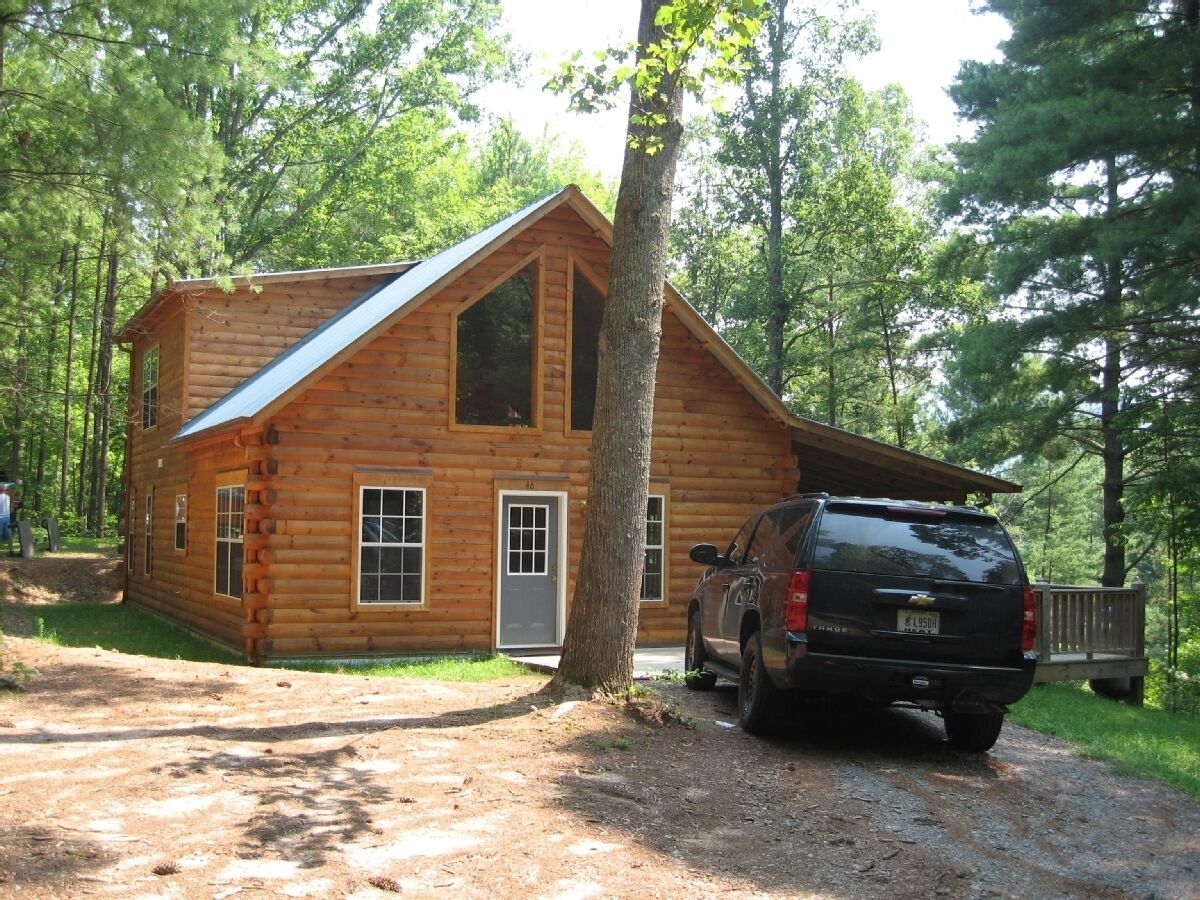 A log cabin with a metal roof, a front door, and a driveway.