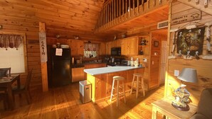 L’intérieur d’une cabane est doté de murs en bois, d’une cuisine équipée d’un réfrigérateur, d’un four à micro-ondes et de tabourets de bar.