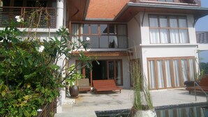 Een huis met twee verdiepingen, een balkon, een zwembad en een tuin.
