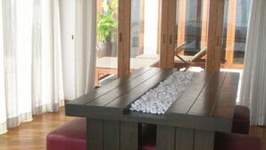 Een houten tafel met een gegranuleerde rand, omringd door rode, beklede zitplaatsen en een glazen scheiding.